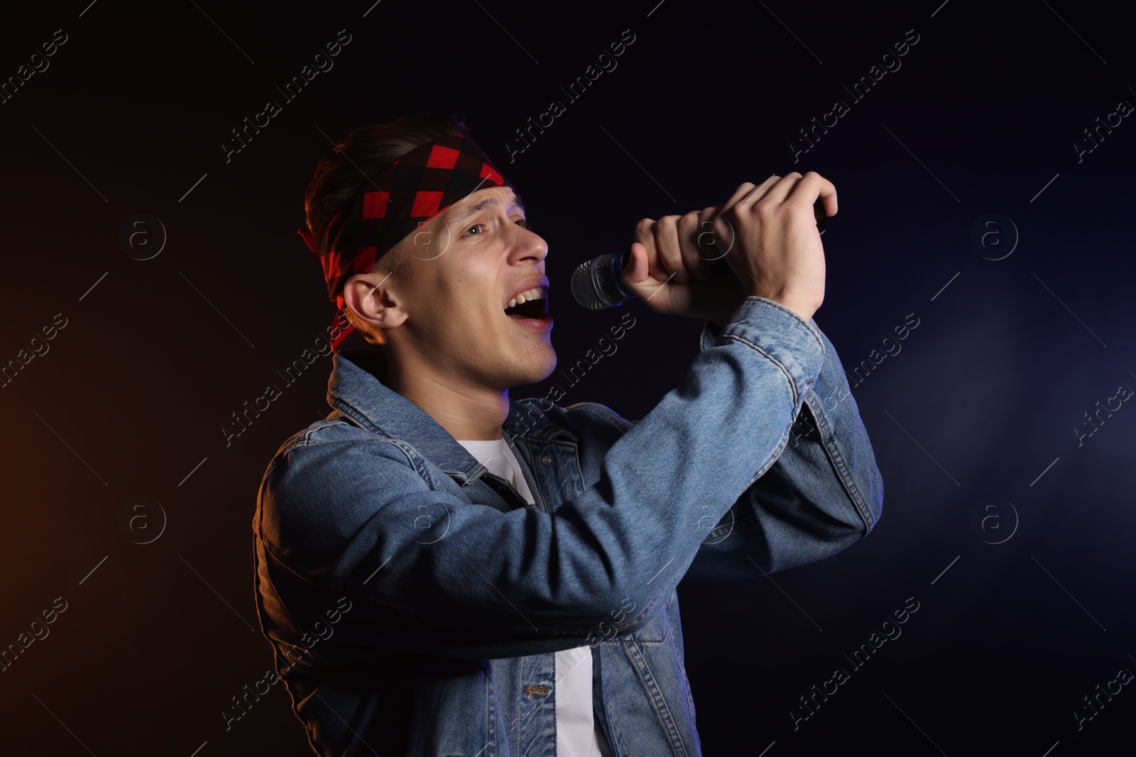 Photo of Talented singer performing on dark background with color light