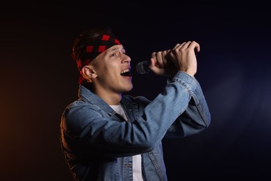 Talented singer performing on dark background with color light