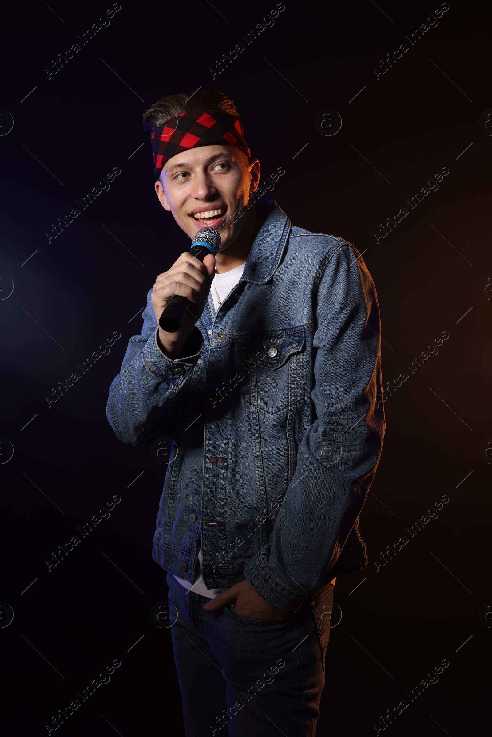 Photo of Talented singer performing on dark background with color light