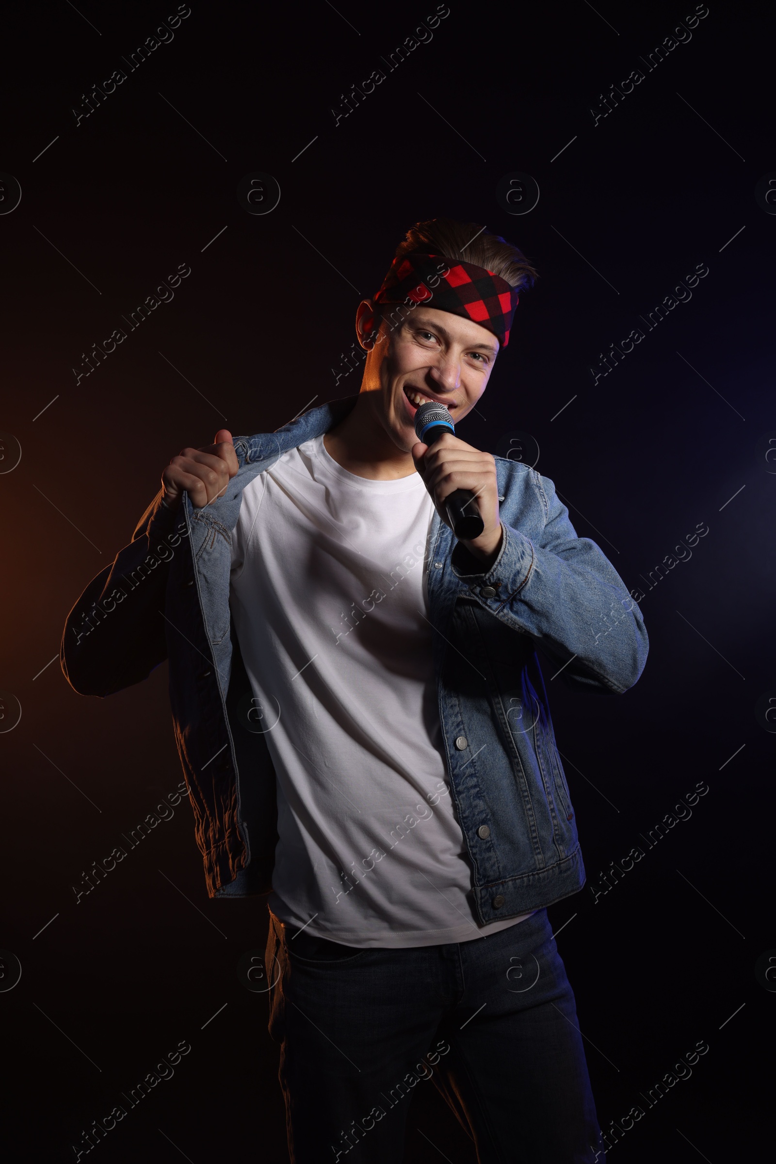 Photo of Talented singer performing on dark background with color light