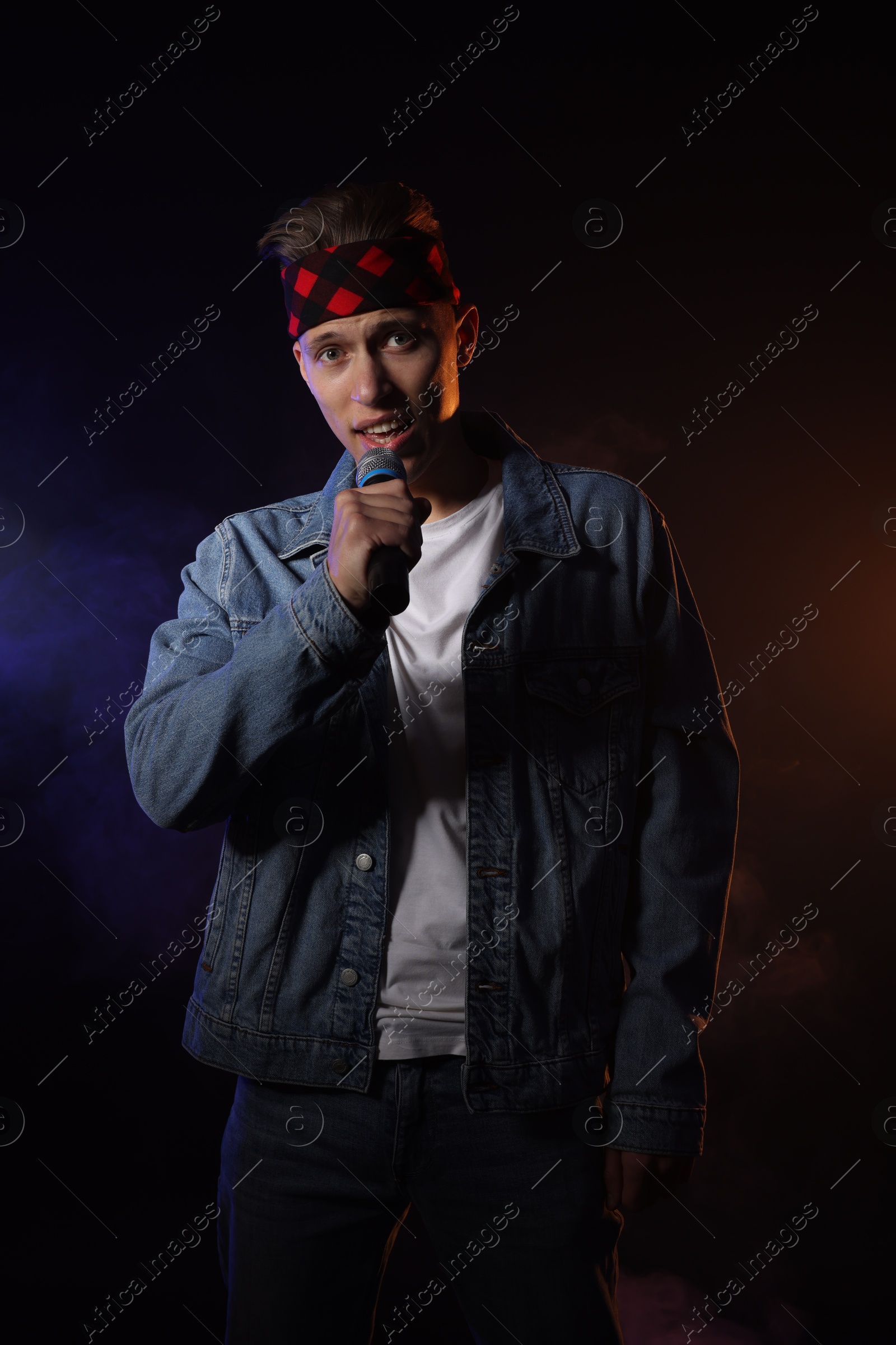 Photo of Talented singer performing on dark background with color lights