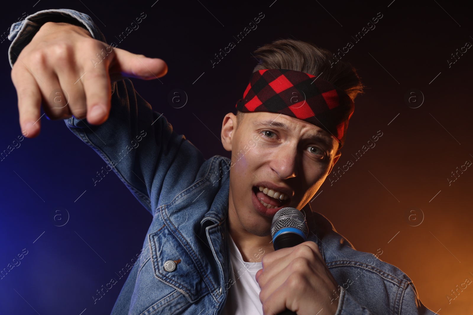 Photo of Talented singer performing on dark background with color lights