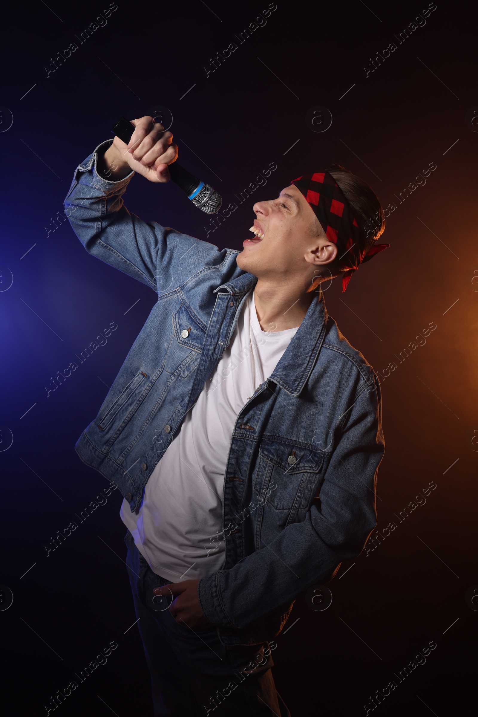 Photo of Talented singer performing on dark background with color lights