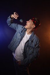 Photo of Talented singer performing on dark background with color lights