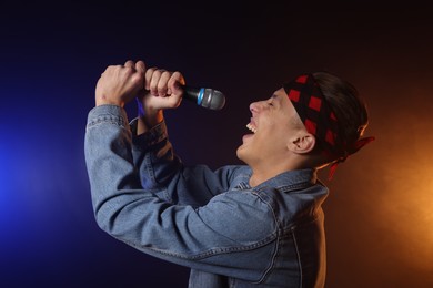 Photo of Talented singer performing on dark background with color lights