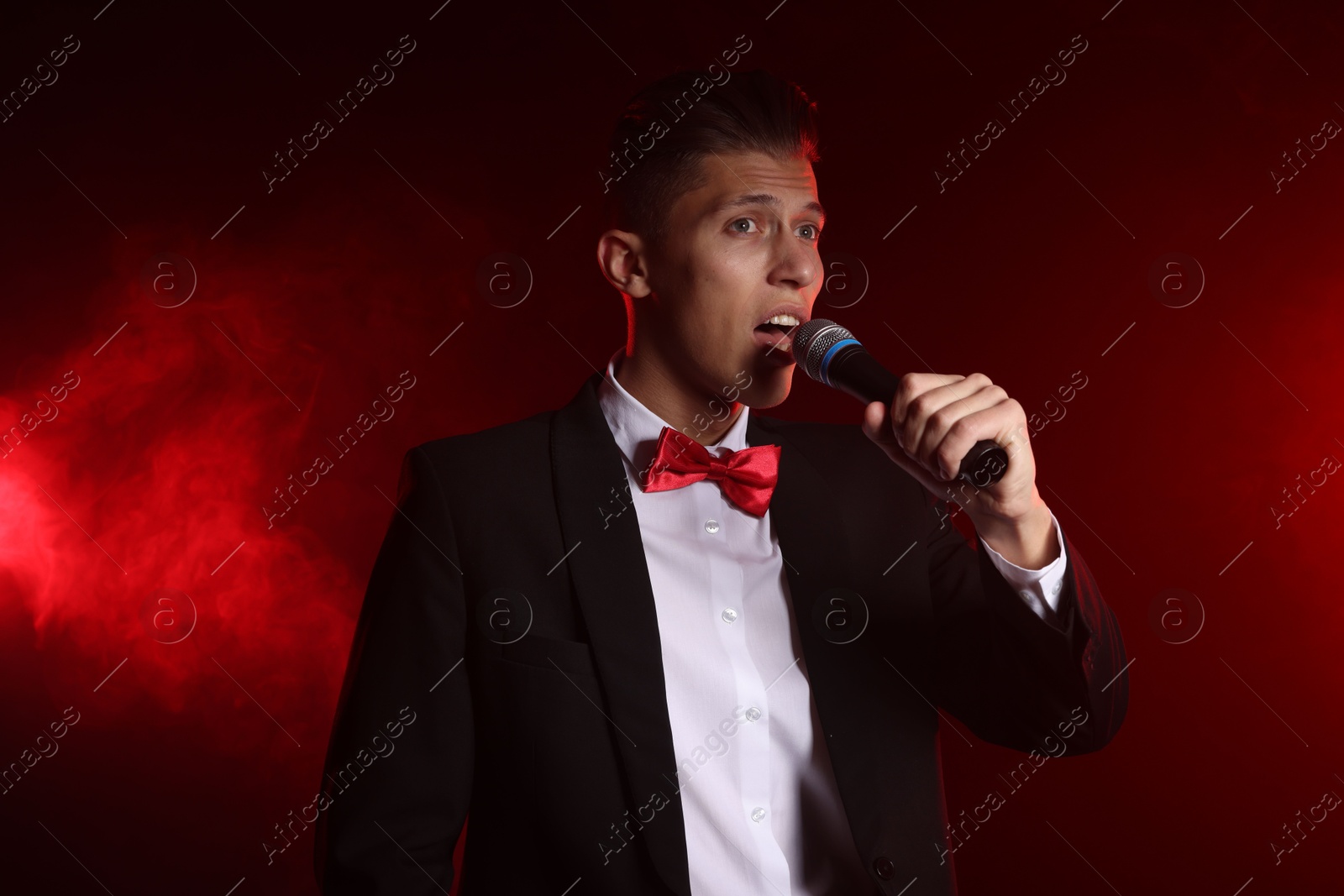 Photo of Talented singer performing on red background with smoke