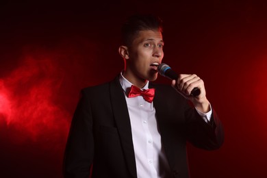 Photo of Talented singer performing on red background with smoke