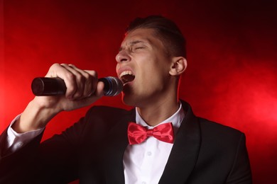 Photo of Talented singer performing on red background with smoke