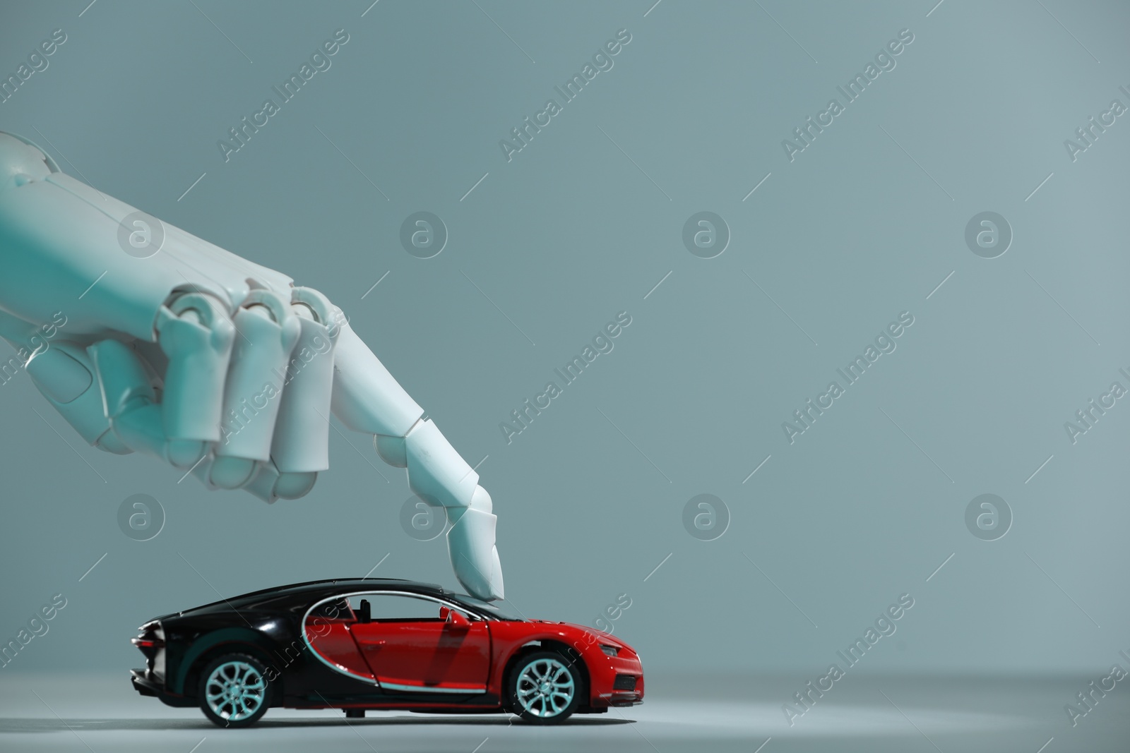 Photo of Artificial intelligence. Robot hand with toy car against grey background, closeup. Space for text