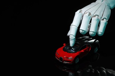 Artificial intelligence. Robot hand with toy car against black background, closeup. Space for text