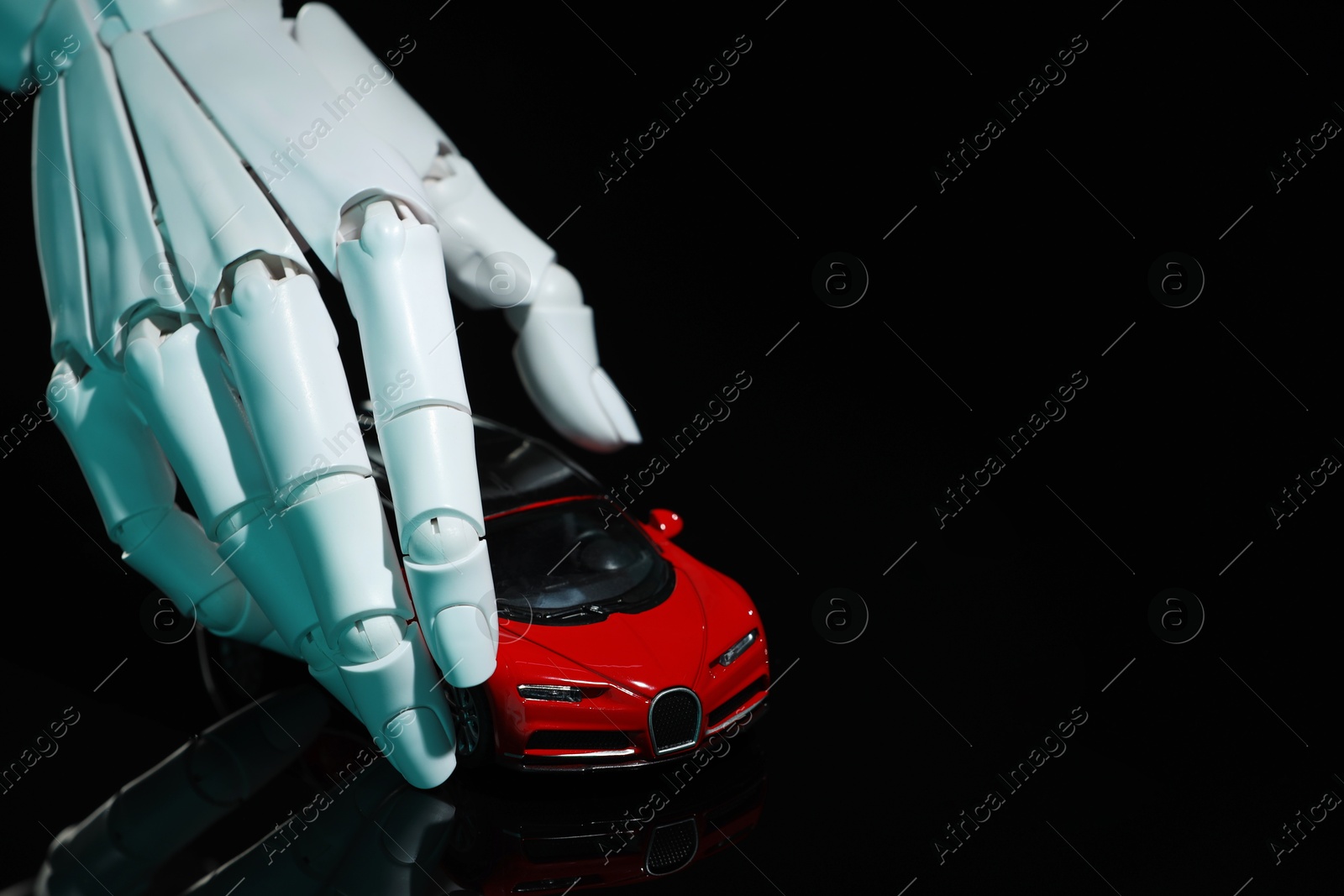 Photo of Artificial intelligence. Robot hand with toy car against black background, closeup. Space for text