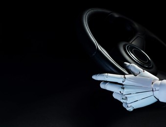 Photo of Artificial intelligence. Robot hand with steering wheel on black background, closeup. Space for text