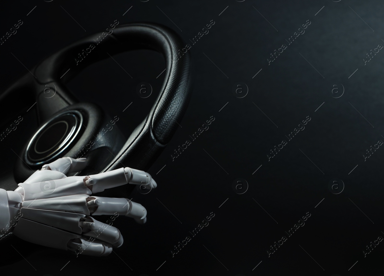 Photo of Artificial intelligence. Robot hand with steering wheel on black background, closeup. Space for text