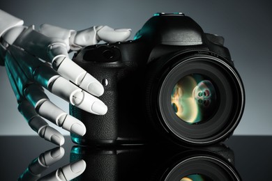 Photo of Artificial intelligence. Robot hand with photo camera against grey background, closeup