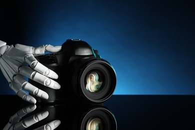 Photo of Artificial intelligence. Robot hand with photo camera against dark blue background, closeup. Space for text