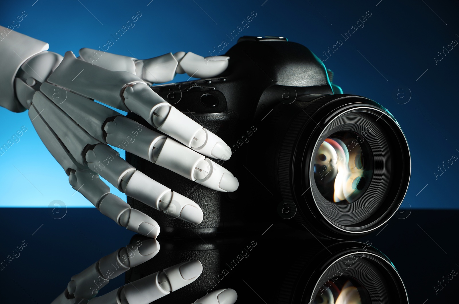 Photo of Artificial intelligence. Robot hand with photo camera against dark blue background, closeup