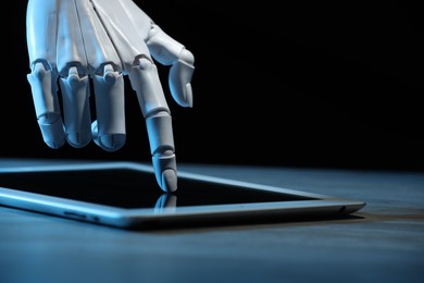 Photo of Artificial intelligence. Robot hand using tablet at table, closeup