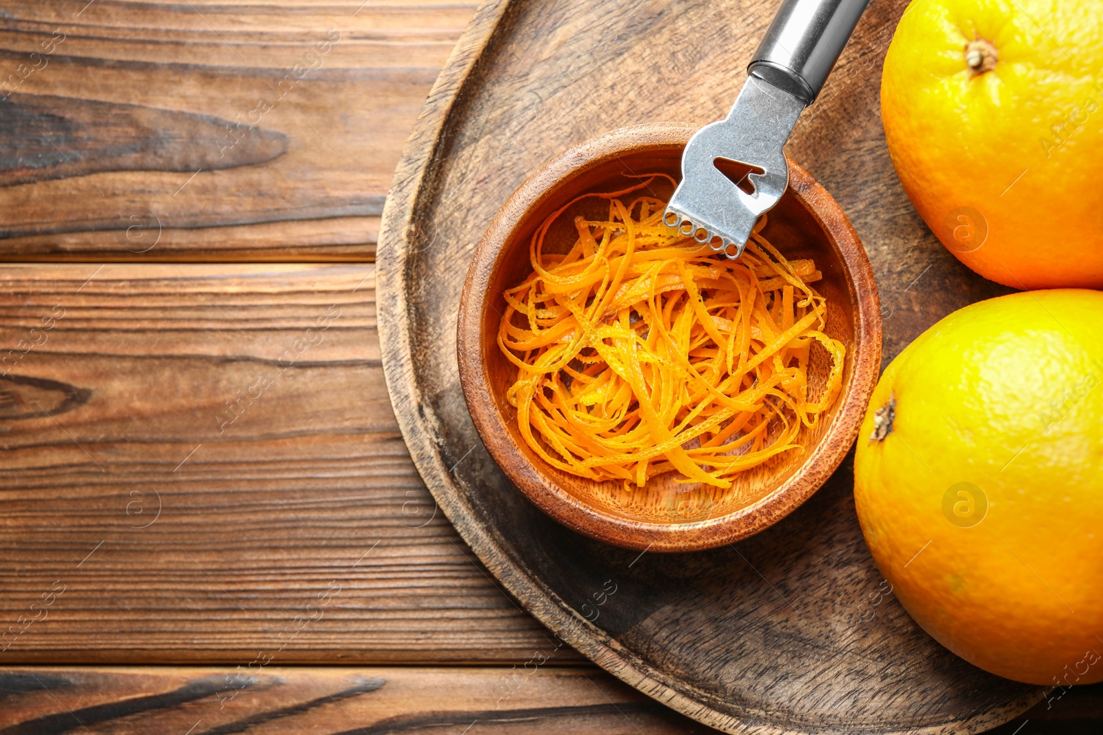 Photo of Orange zest, zester tool and fresh fruits on wooden table, top view. Space for text