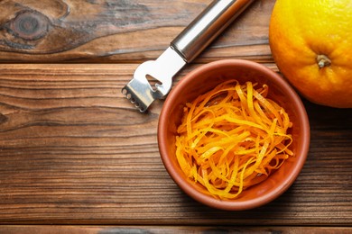 Photo of Orange zest, zester tool and fresh fruit on wooden table, flat lay. Space for text