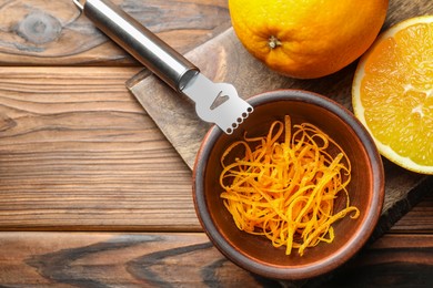 Photo of Orange zest, zester tool and fresh fruits on wooden table, top view. Space for text