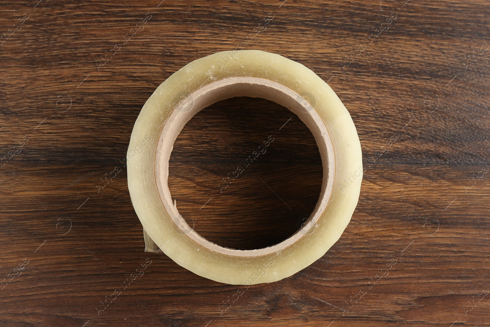 Photo of One adhesive tape on wooden table, top view