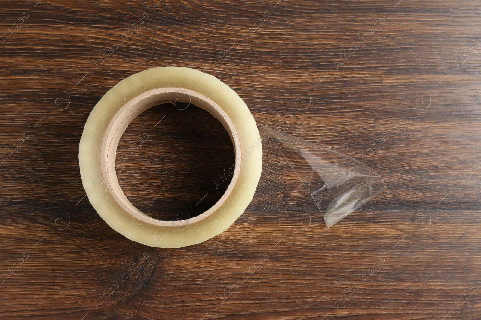 Photo of One adhesive tape on wooden table, top view. Space for text