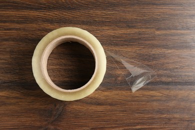 Photo of One adhesive tape on wooden table, top view. Space for text