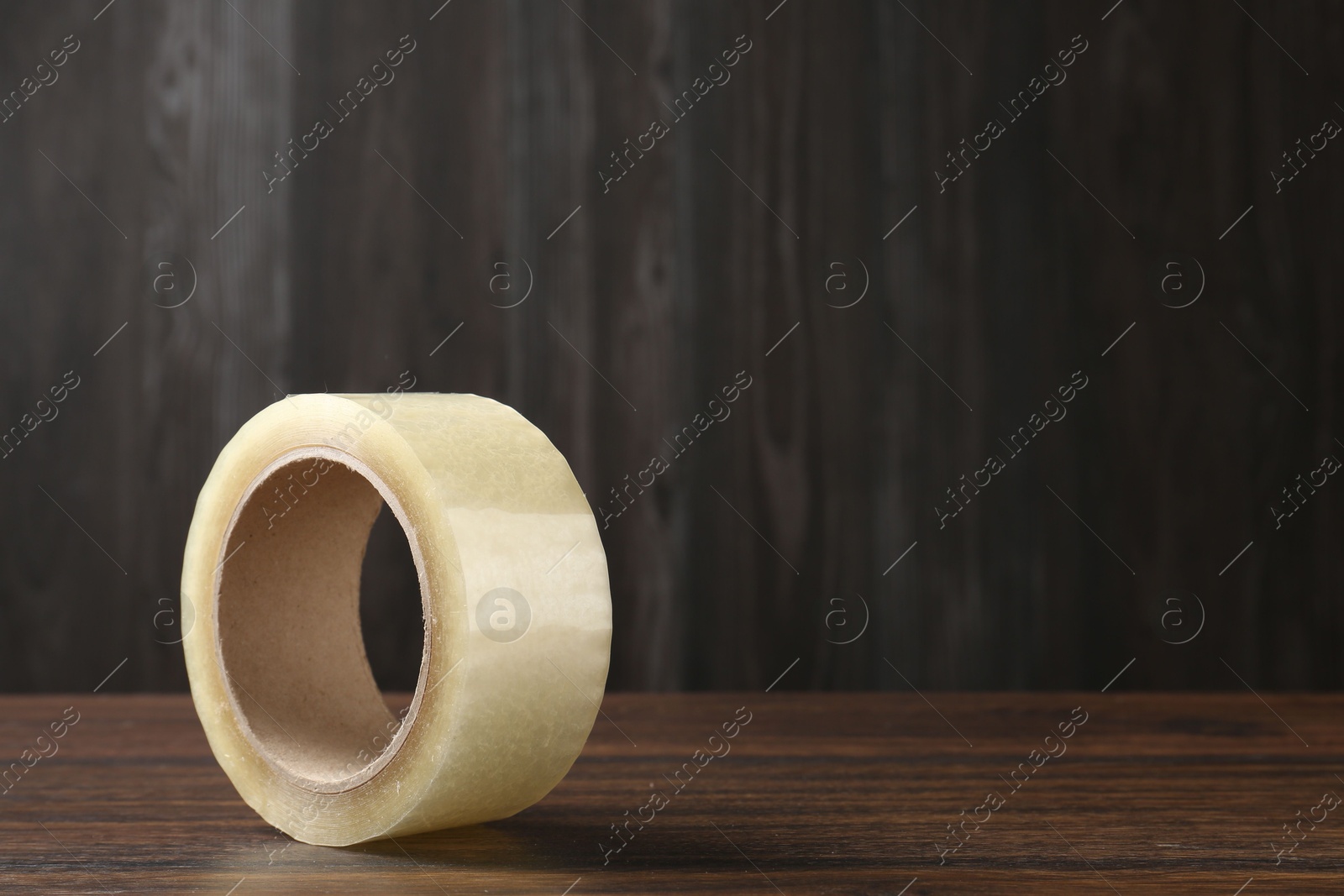 Photo of One adhesive tape on wooden table, closeup. Space for text