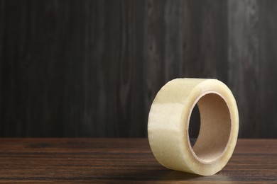 Photo of One adhesive tape on wooden table, closeup. Space for text