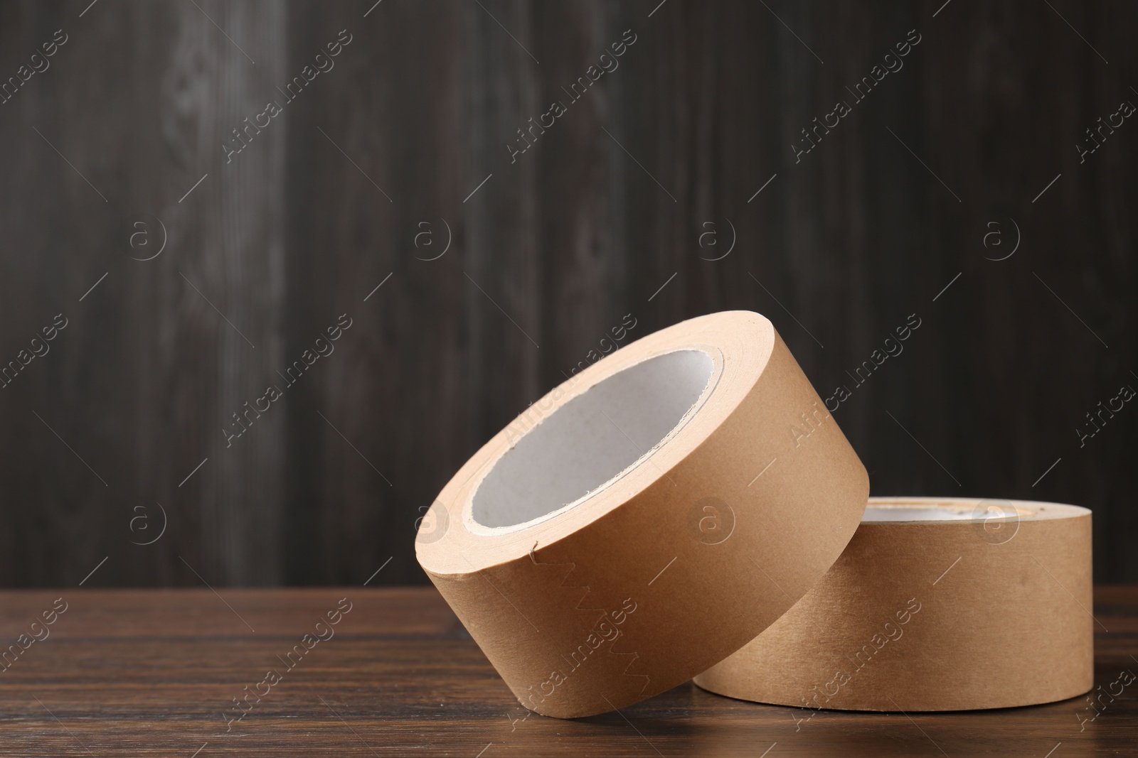 Photo of Two masking tapes on wooden table, closeup. Space for text