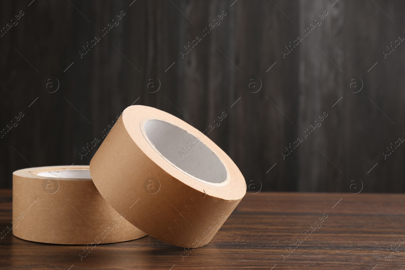 Photo of Two masking tapes on wooden table, closeup. Space for text