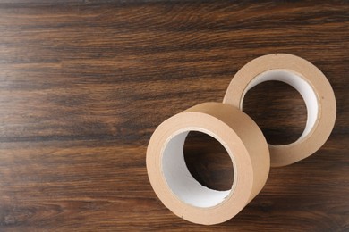 Photo of Two masking tapes on wooden table, top view. Space for text