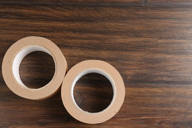 Photo of Two masking tapes on wooden table, top view. Space for text