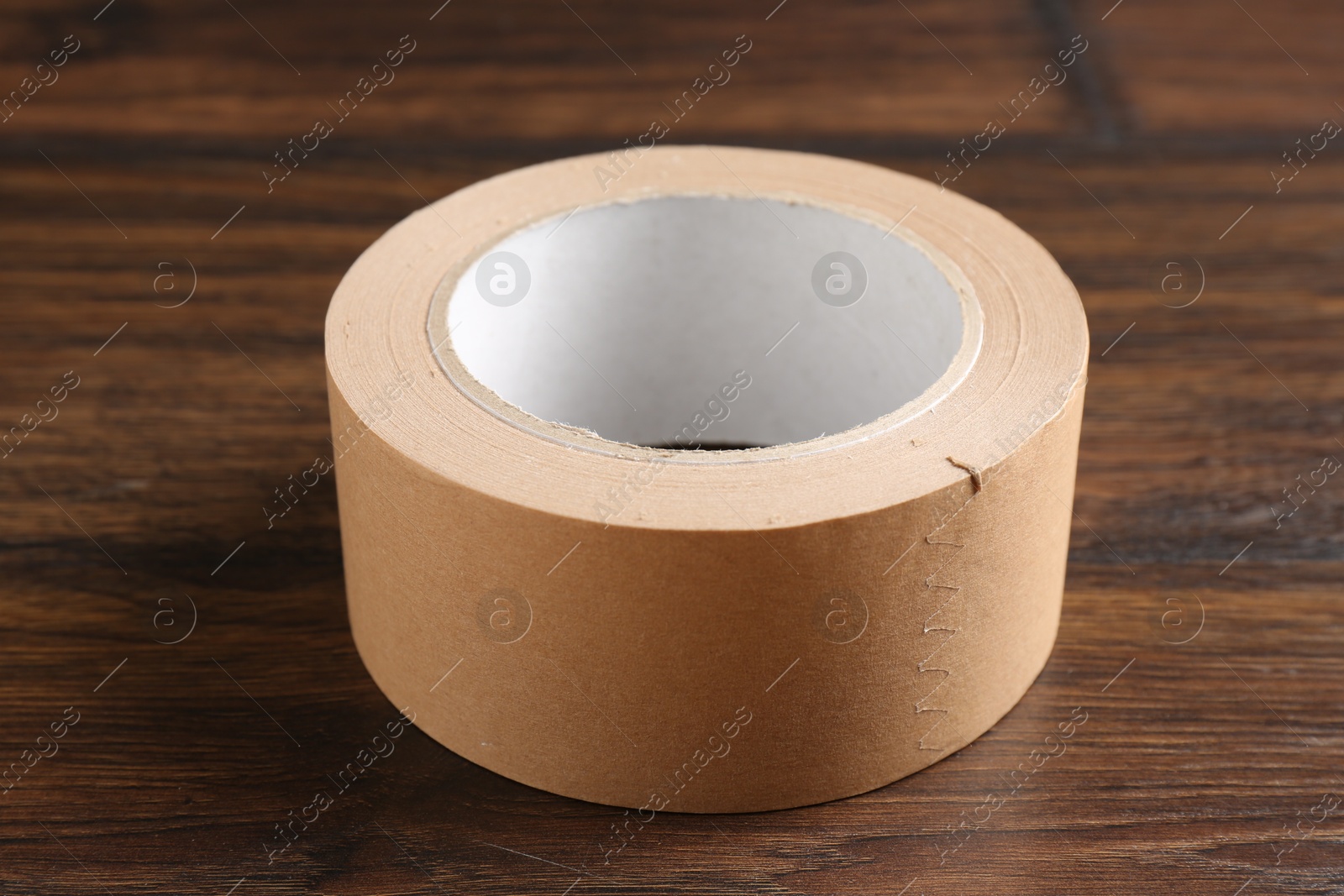 Photo of One masking tape on wooden table, closeup