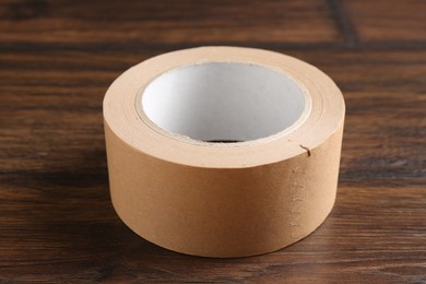 Photo of One masking tape on wooden table, closeup