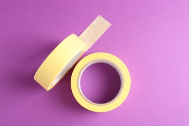 Rolls of masking tapes on violet background, top view