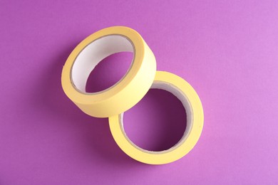 Rolls of masking tapes on violet background, top view