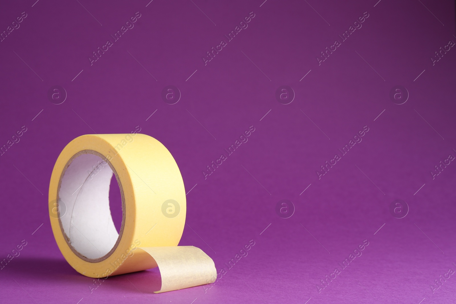 Photo of Roll of masking tape on violet background, space for text