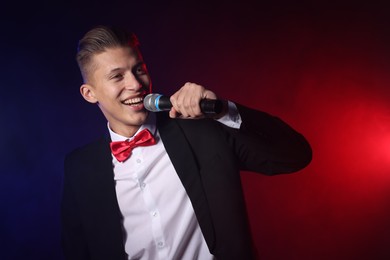 Photo of Talented singer performing on dark background with color lights