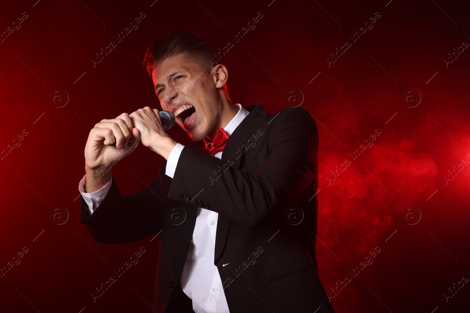 Photo of Talented singer performing on red background with smoke