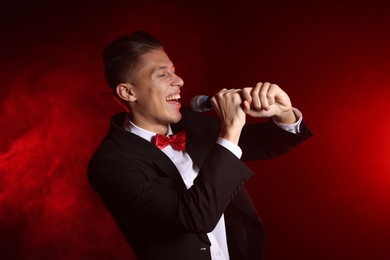 Photo of Talented singer performing on red background with smoke