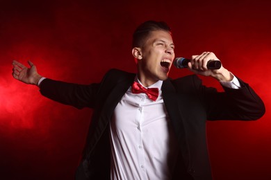 Photo of Talented singer performing on red background with smoke