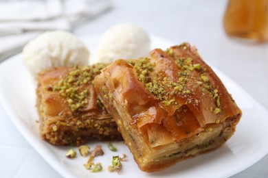 Delicious baklava with crushed nuts and ice cream on white table, closeup