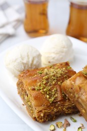 Delicious baklava with crushed nuts and ice cream on white table, closeup