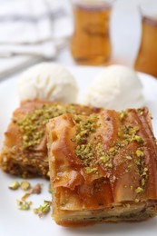 Delicious baklava with crushed nuts and ice cream on table, closeup