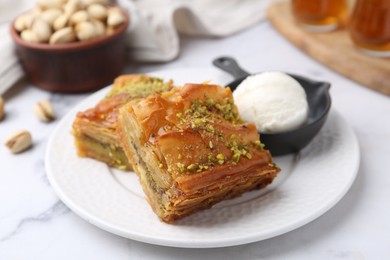 Photo of Delicious baklava with crushed nuts and ice cream on white marble table, closeup