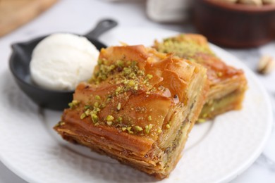 Photo of Delicious baklava with crushed nuts and ice cream on white table, closeup