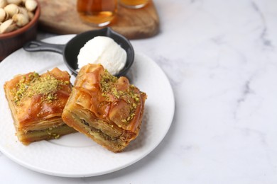 Delicious baklava with crushed nuts and ice cream on white marble table, closeup. Space for text