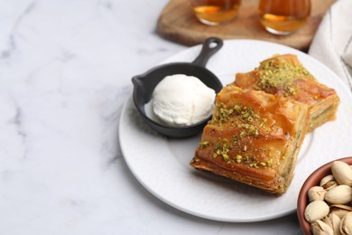 Photo of Delicious baklava with crushed nuts and ice cream on white marble table, closeup. Space for text