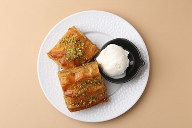 Delicious baklava with crushed nuts and ice cream on beige table, top view